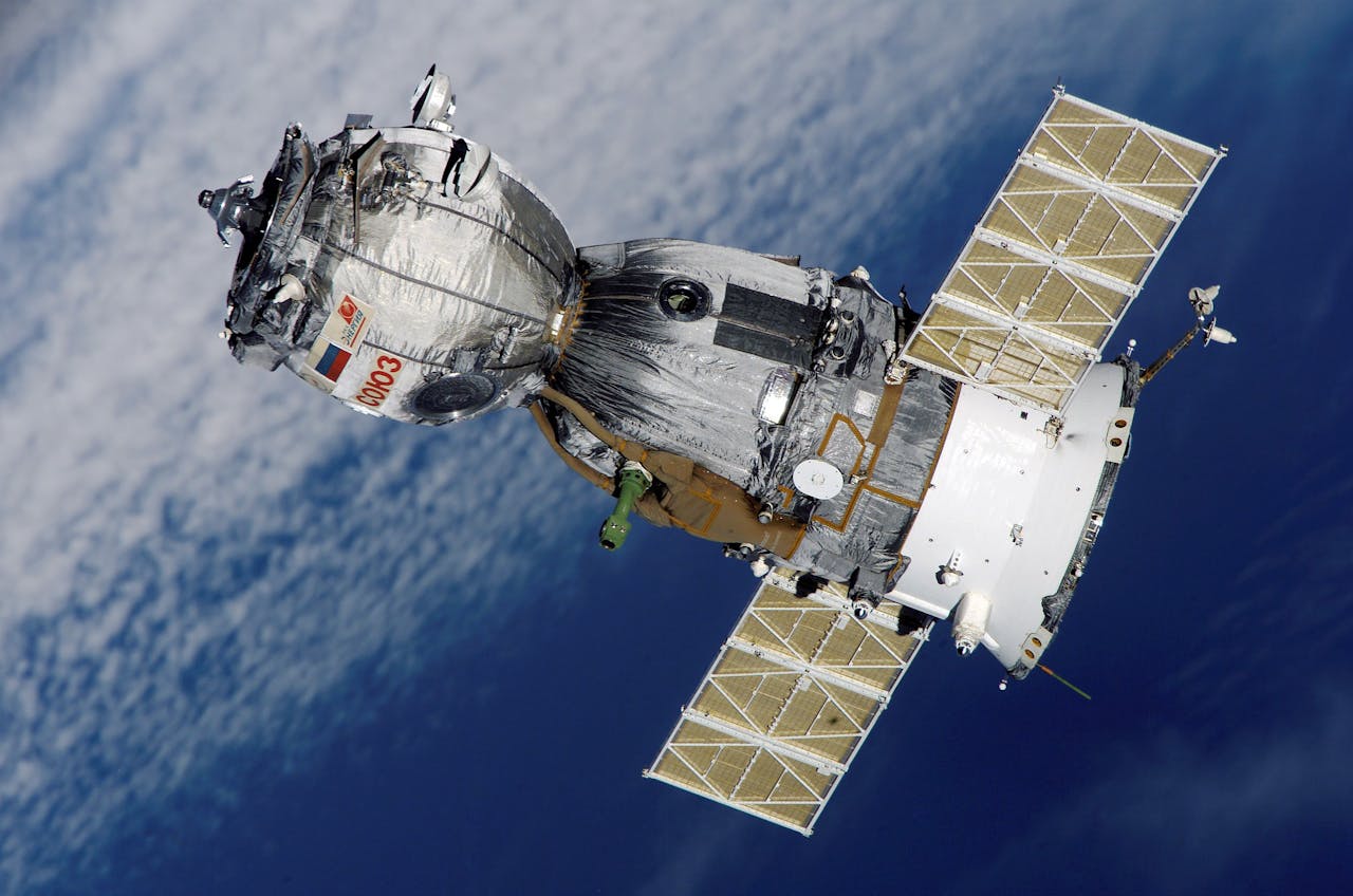 About Close-up of Soyuz spacecraft orbiting Earth with solar panels extended, showcasing space exploration technology.
